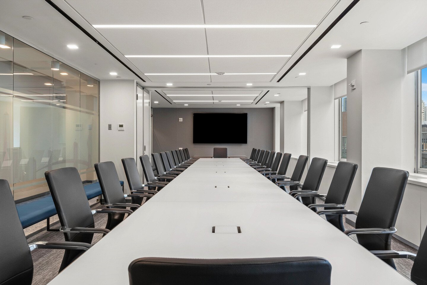 A long conference table surrounded by minimalist black conference chairs in the New York Bankers Association office, furnished by Benhar.