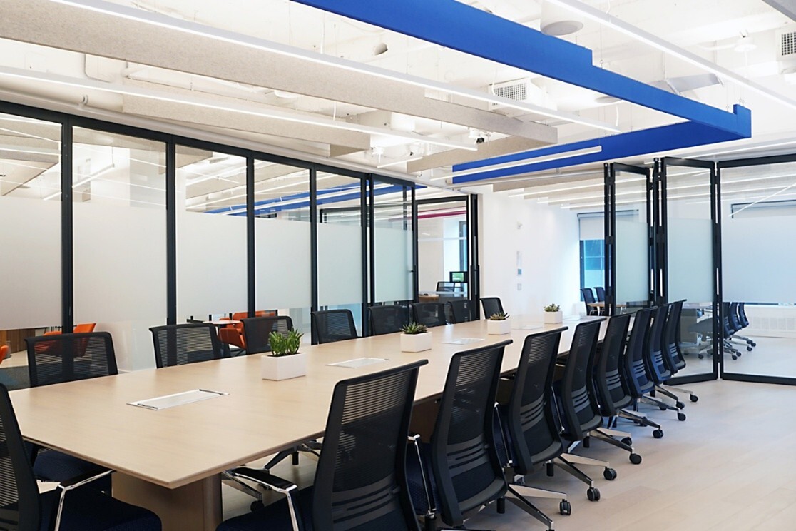 a conference room with folding and sliding glass walls that open the room to the rest of the office