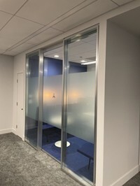 a double-glazed framed glass wall acts as the entrance to a private office
