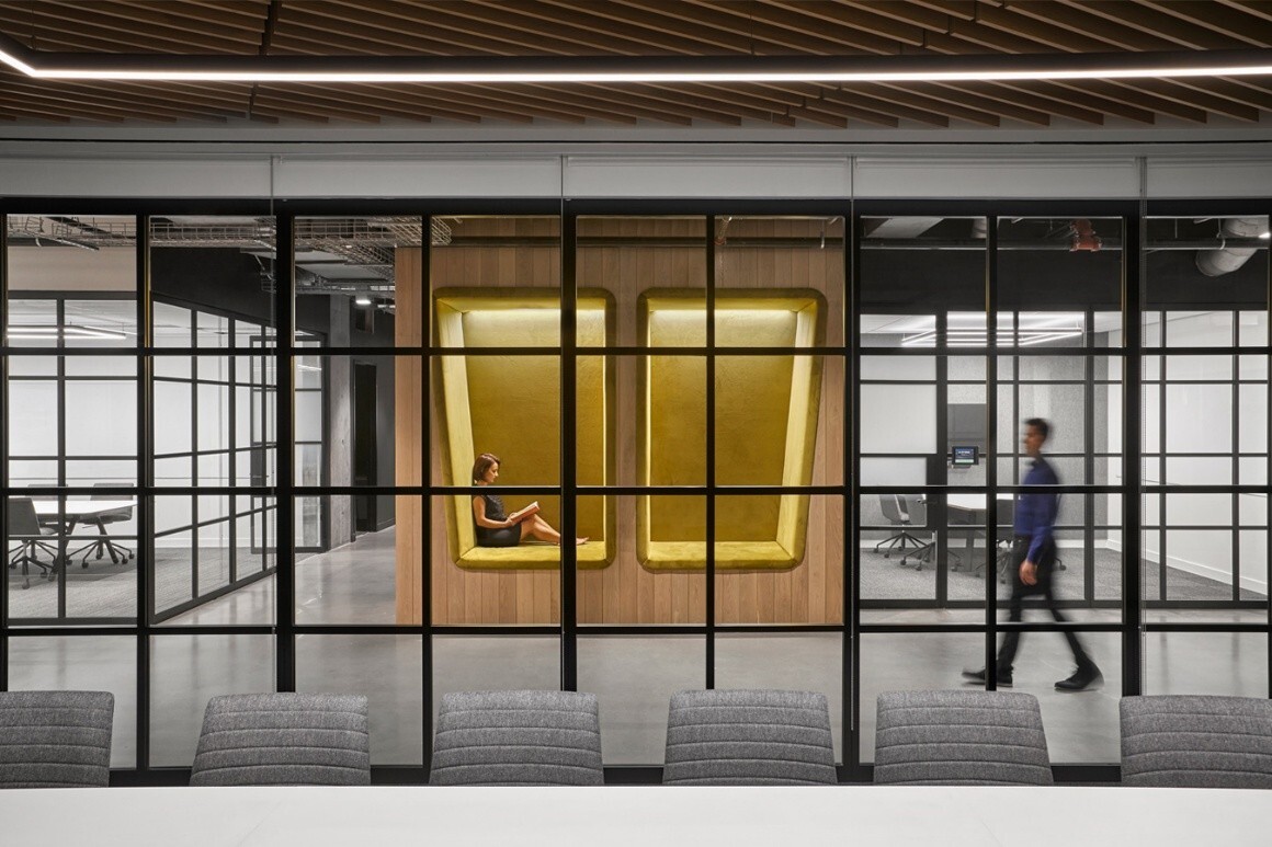a framed single-glazed glass wall separates a conference room from a hallway